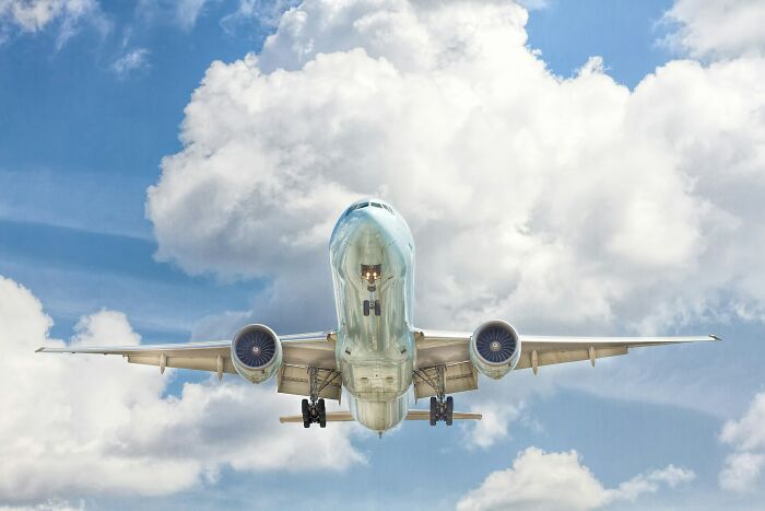 A large passenger airplane ascending into a blue sky with fluffy white clouds, representing cabin crew questions.