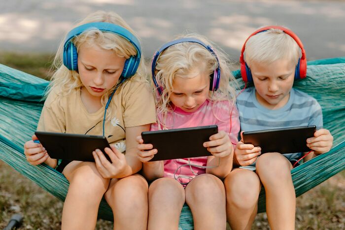 Cabin crew questions: Three children with headphones and tablets, symbolizing the unhinged questions cabin crew get.
