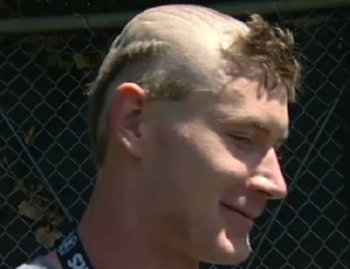 A man with a bold, partially shaved hairstyle, featuring short, spiky hair on top and a shaved back.