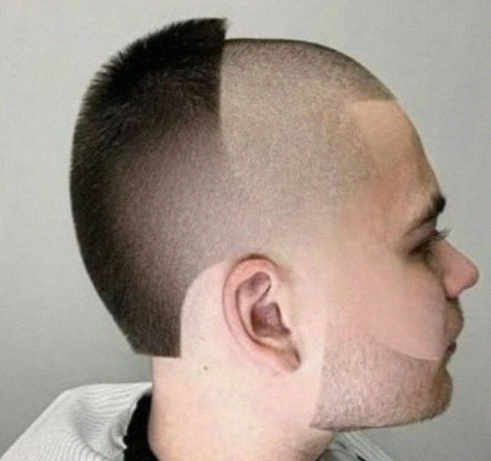 A man with a half-shaved bold hairstyle, featuring a sharp, asymmetrical line across his head.