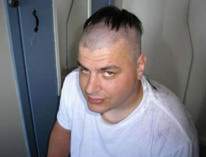 A man with a partially shaved head, featuring a very short, bold hairstyle on top.
