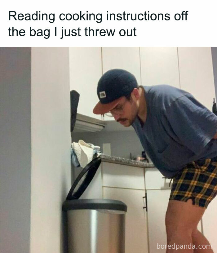 A man in a baseball cap and plaid shorts looks into a trash can in a kitchen, a hilarious meme.
