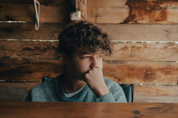 A young boy with curly hair looking away thoughtfully, portraying a child potentially affected by a horrible parent.