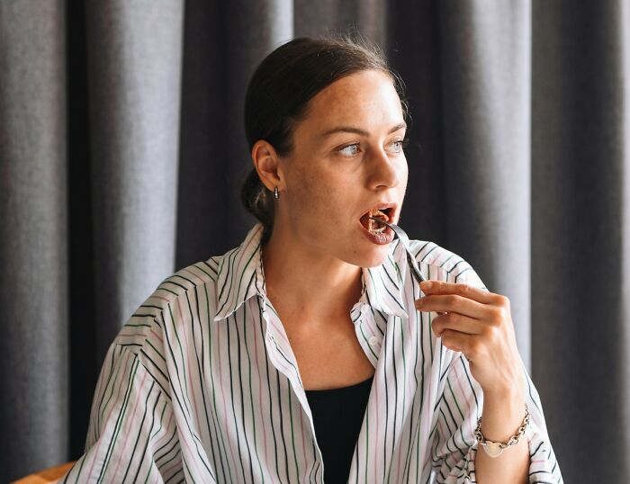 A woman eating thoughtfully, demonstrating a mindful approach to food consumption, a common poverty habit.