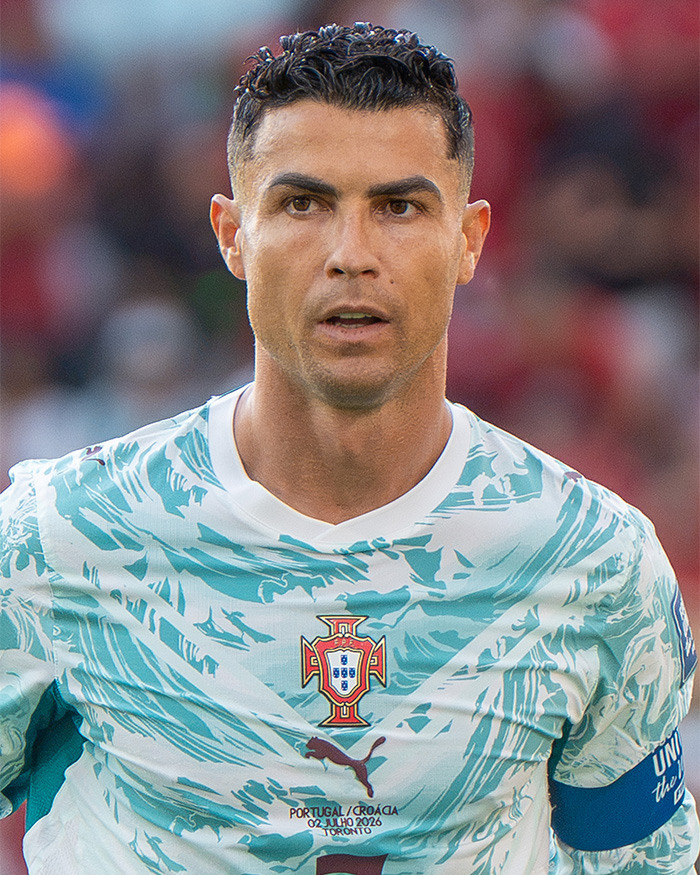 Cristiano Ronaldo in a light blue patterned jersey, looking directly, as his partner Georgina Rodriguez faces body-shamers.