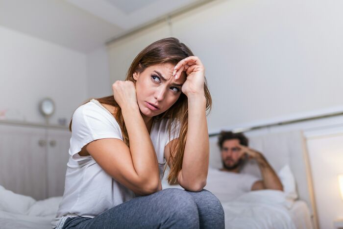 A woman looking upset while her boyfriend is in the background after he said something she could never come back from.