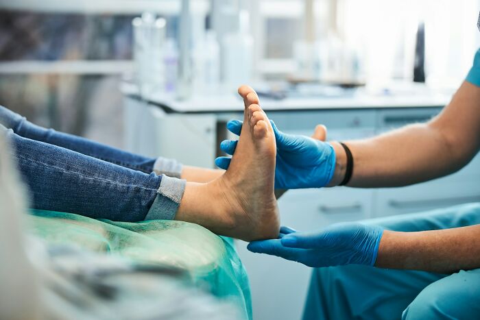 A doctor in blue gloves examines a patient's foot, illustrating a medical examination for diagnoses.