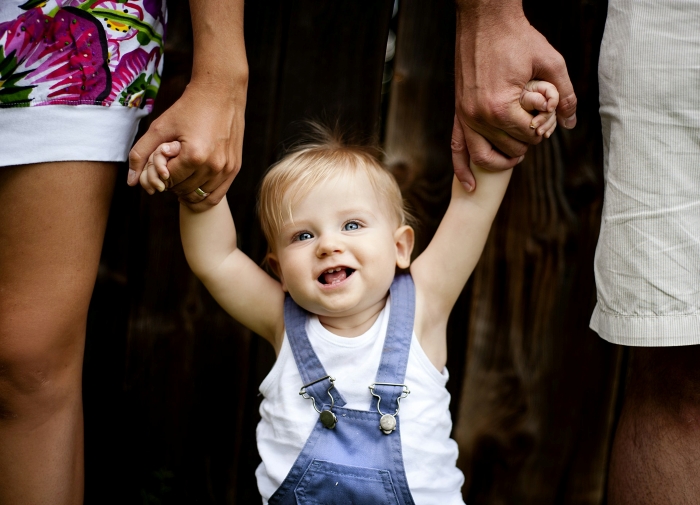 A happy baby is held by parents hands, symbolizing the desire to conceive and marriage.