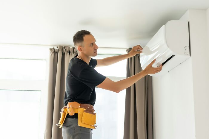 A man installing an air conditioner, not related to the spicy personal details of coworkers.