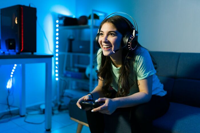 A happy woman playing video games with a headset on, showing a truth about being married.