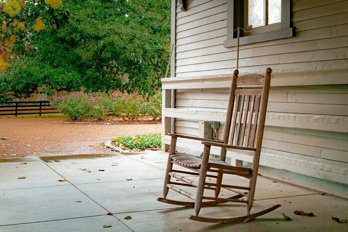 An empty wooden rocking chair on a porch, emphasizing interesting neighbors.