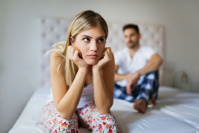 A woman looking upset while a man sits in the background, illustrating some truths about being married.