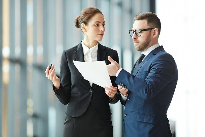 Two professionals in business attire, discussing documents and delivering sick burns with their critiques.