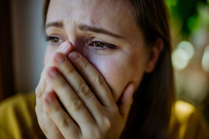 A woman crying, covering her mouth with hands, portraying scary true stories.