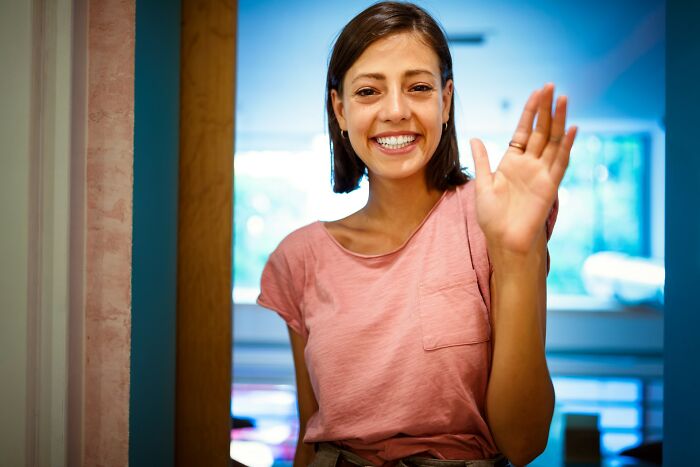 A smiling woman waving, happy to leave behind breakup-worthy things partners did.