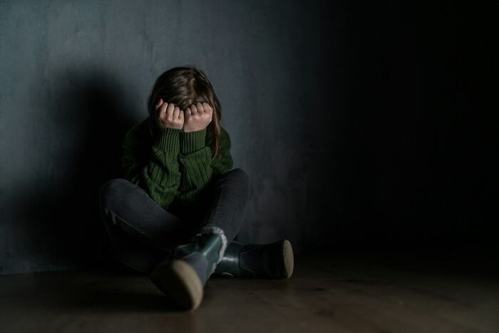 A child sits on the floor, head in hands, seemingly scared by creepy true stories that question reality.