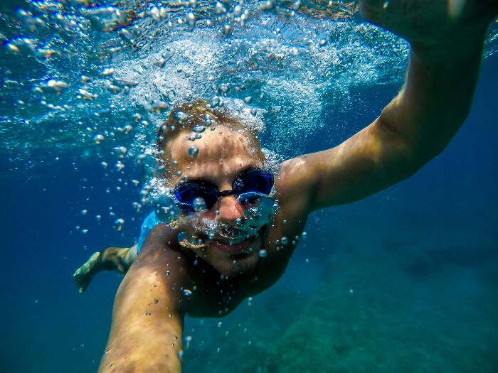 Man swimming underwater with goggles, demonstrating a skill that genuinely changed his life.