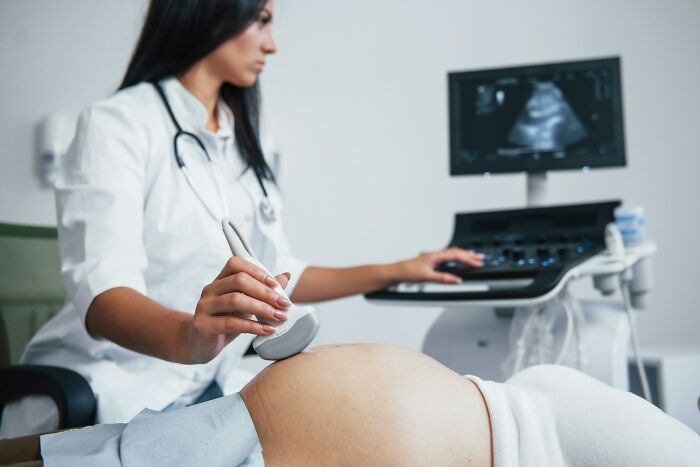 A female doctor performs an ultrasound on a pregnant woman, often delivering difficult diagnoses.