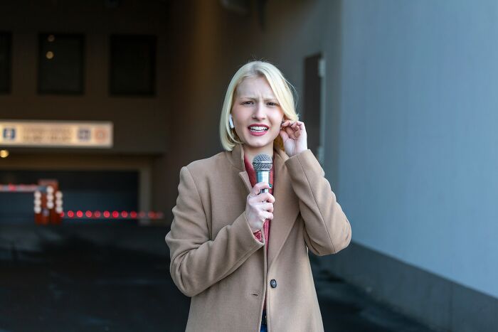 Female reporter with a microphone looking stressed, reflecting on dating a celebrity.