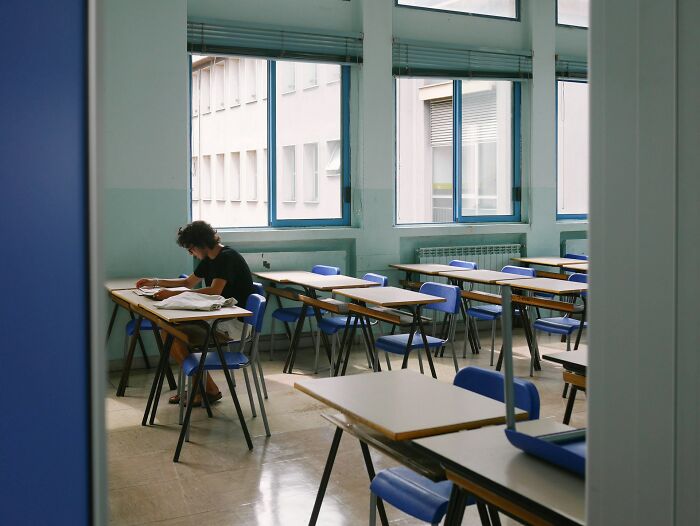 A student sits alone in a classroom, representing the independence and freedom of college life.