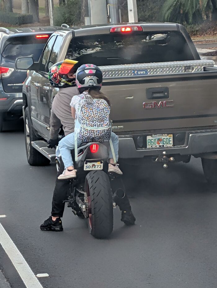 A parent and child ride a motorcycle, showcasing a wrong way to solve a transportation problem.