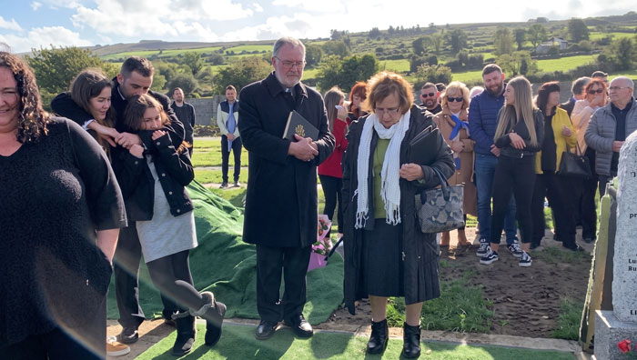 Attendees at a funeral, some smiling and others embracing, celebrating the man's final wish. Attendees at a funeral, some smiling and others embracing, celebrating the man's final wish.