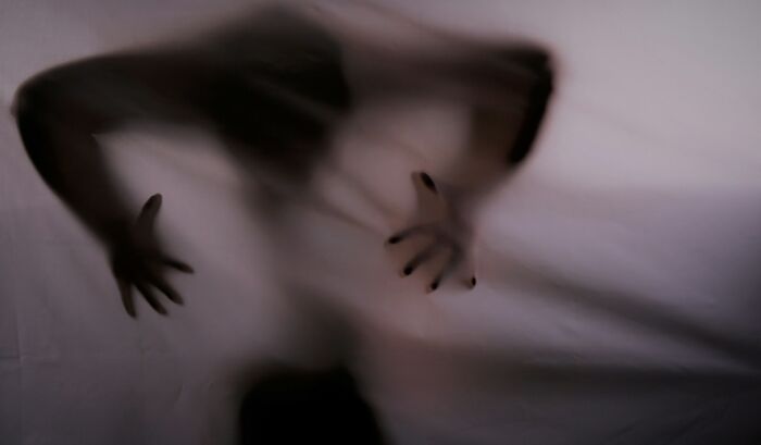A person's silhouette is visible through a white sheet, with hands reaching out. Another one of the interesting neighbors.
