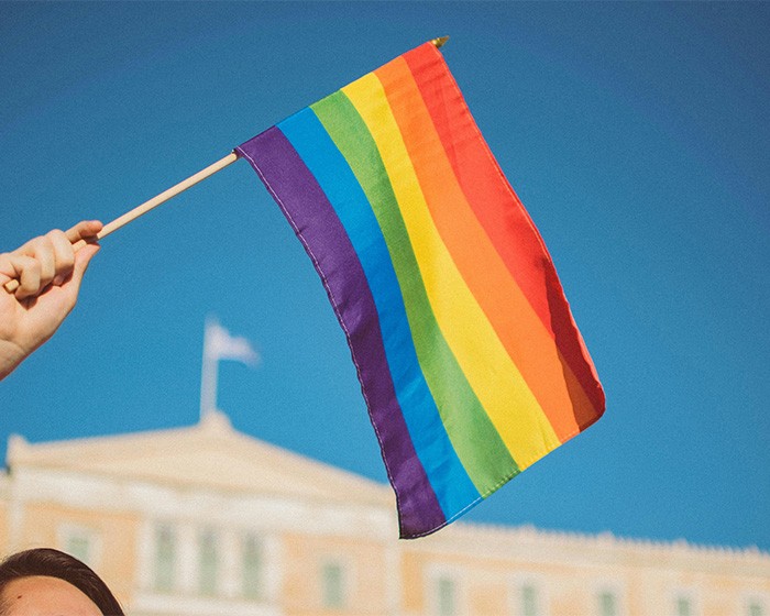 A hand waving a rainbow flag, symbolizing support for transgender customers in the hair salon dispute. A hand waving a rainbow flag, symbolizing support for transgender customers in the hair salon dispute.
