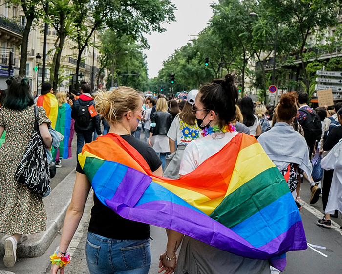 People walking with a rainbow flag, representing support for transgender customers in contrast to the hair salon owner. People walking with a rainbow flag, representing support for transgender customers in contrast to the hair salon owner.
