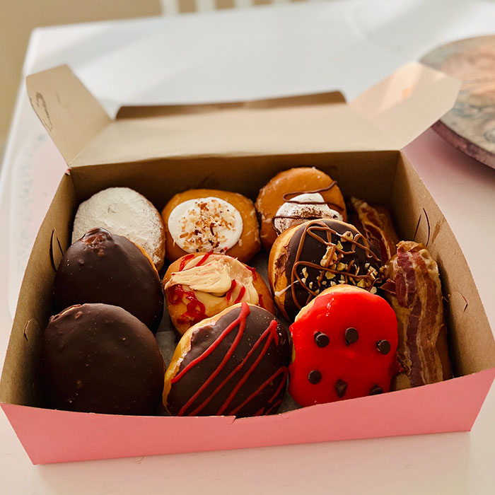 An open box of assorted donuts, a sweet harmless secret that warms hearts.