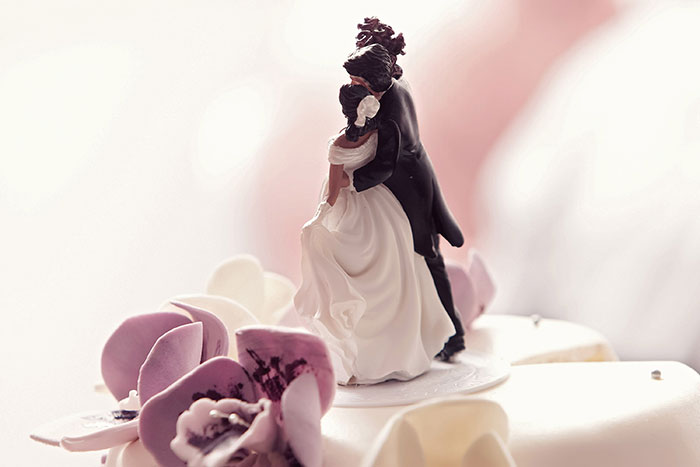 A wedding cake topper featuring a couple embracing, symbolizing the harmless secrets people keep to warm hearts.