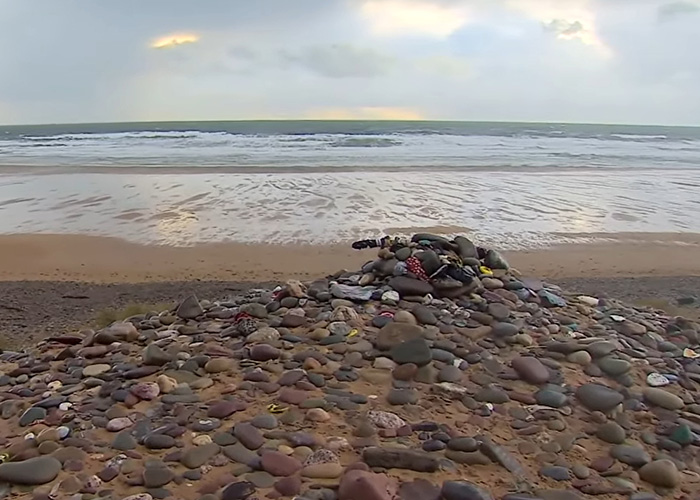 A pile of stones and items on a beach, forming a shrine by Harry Potter fans.