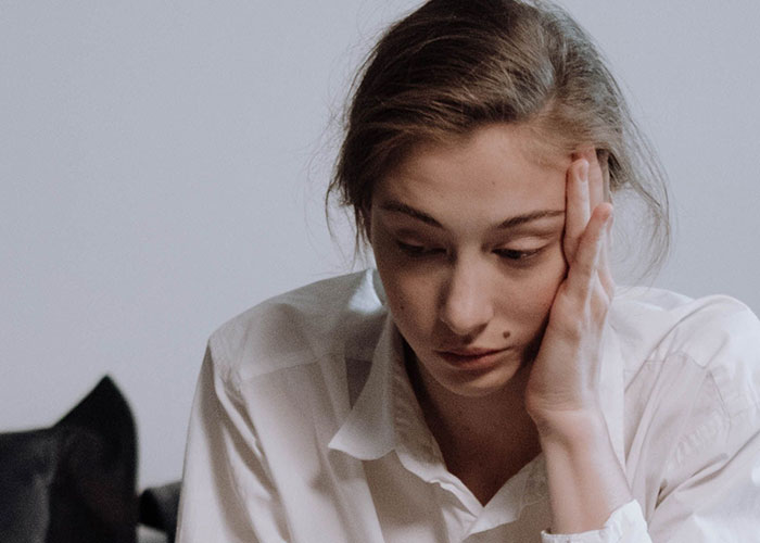 A young woman with a mole on her cheek looks concerned, experiencing unusual symptoms. Doctors often stop and stare.