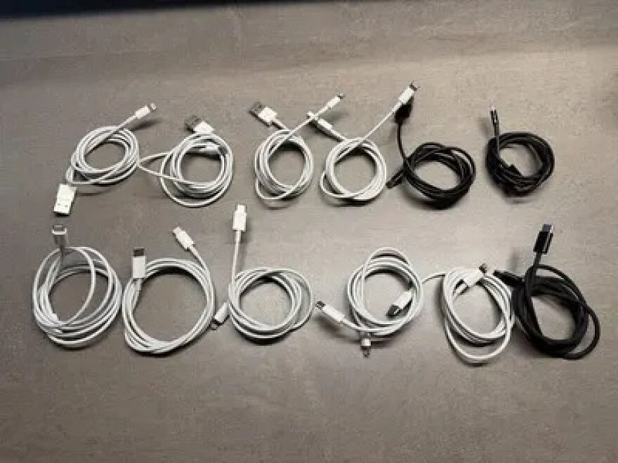Several neatly coiled charging cables, both white and black, lay on a grey surface, a weird side hustle.