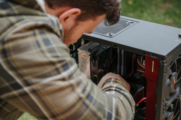 A man fixing a computer, focused on the internal components. Harmless-looking things can be dangerous.