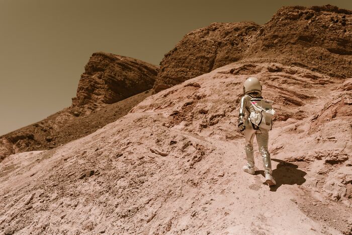 A person in a space suit climbing a rocky, barren landscape, depicting harmless-looking things that can be way more dangerous.