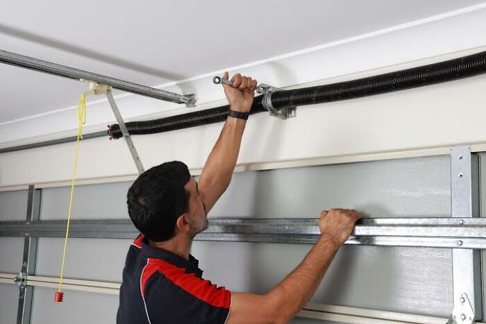 A man working on the dangerous springs of a garage door, which can be more dangerous than people realize.