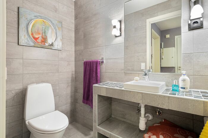 A contemporary bathroom with a toilet, sink, mirror, and purple towel. Harmless-looking things can be more dangerous.