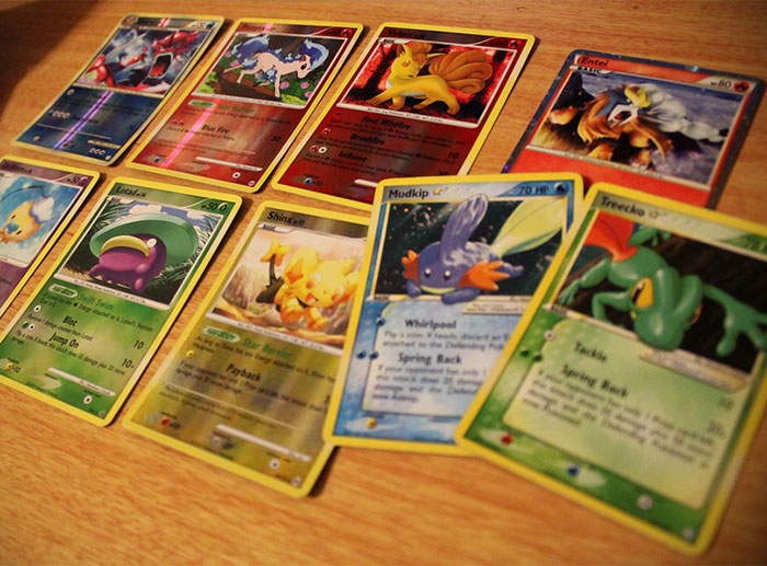 A close-up of various Pokémon cards spread out on a wooden surface, showing different characters and abilities.