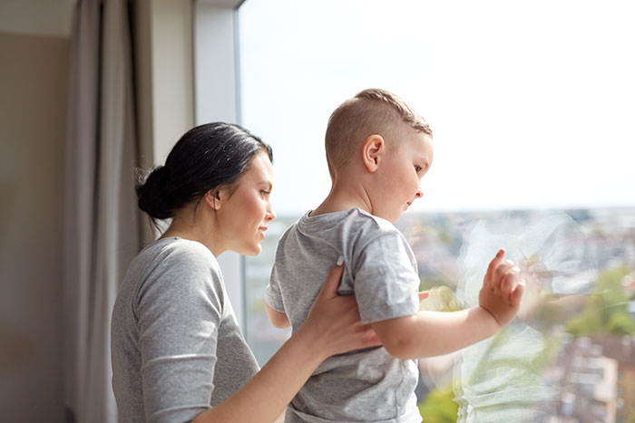 A woman and her stepson look out a window, potentially reflecting on the grandma's accusation of buying love with gifts.