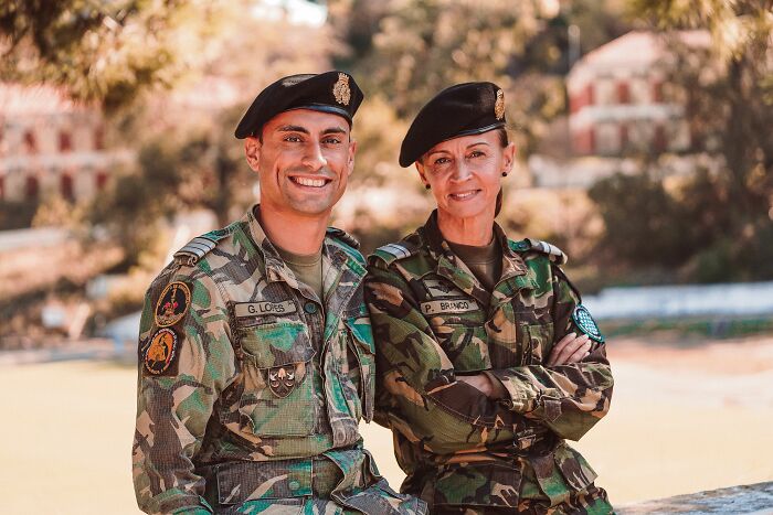 Two military personnel in uniform, a man and a woman, smiling outdoors, for an article about funny encounters with tourists.