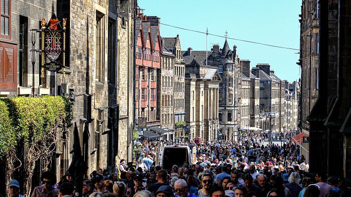 A crowded street in Edinburgh, Scotland, showcasing many people and historic buildings, relevant to embarrassing encounters.