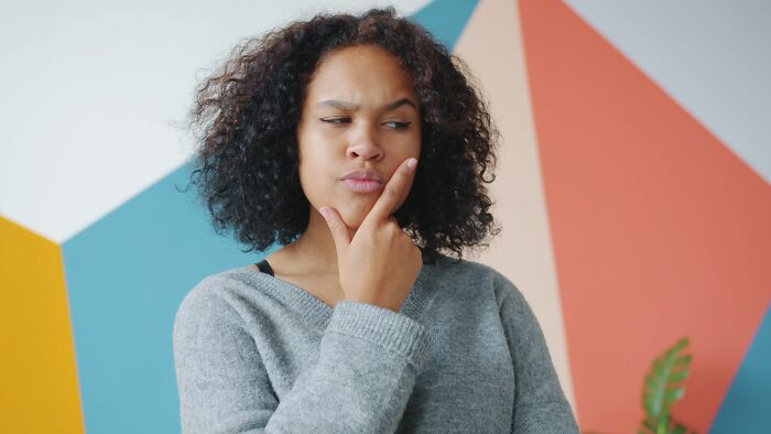 A woman with a thoughtful expression reflects on funny encounters with American tourists.