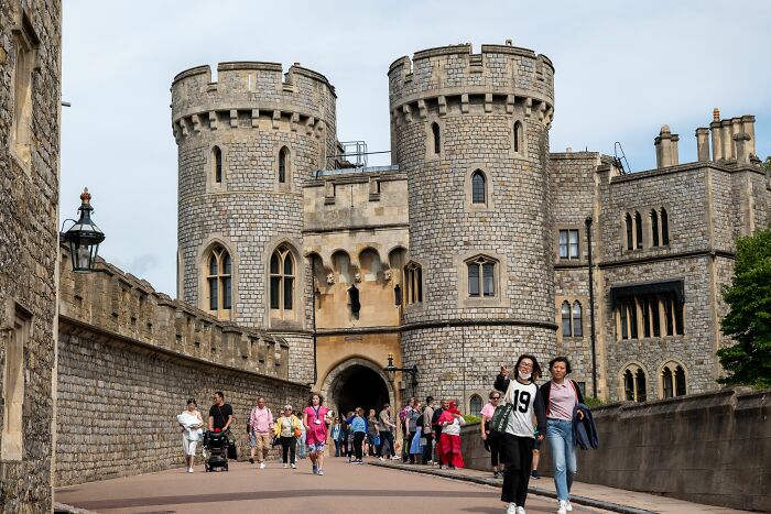 Tourists walk by a castle, capturing the essence of American tourists encountering new places.