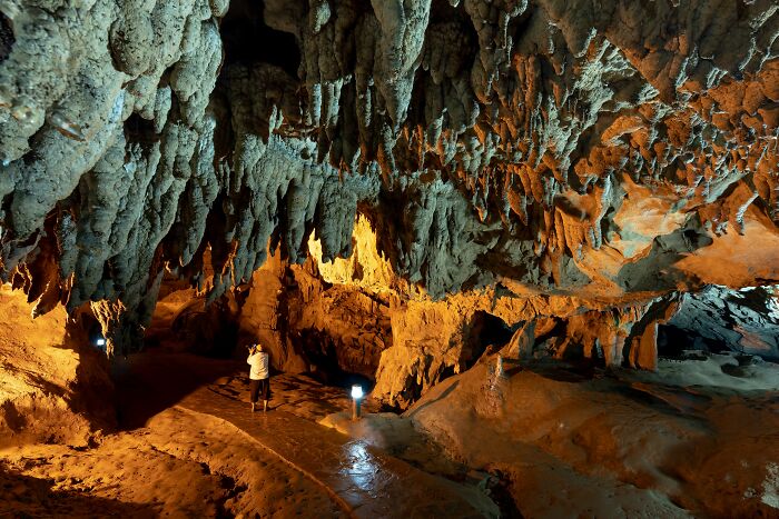 A person exploring a cave, a unique setting for weird and funny encounters with American tourists.