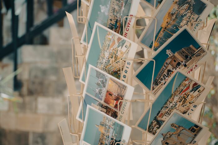 A rotating display rack full of postcards featuring scenic views, often bought by American tourists.