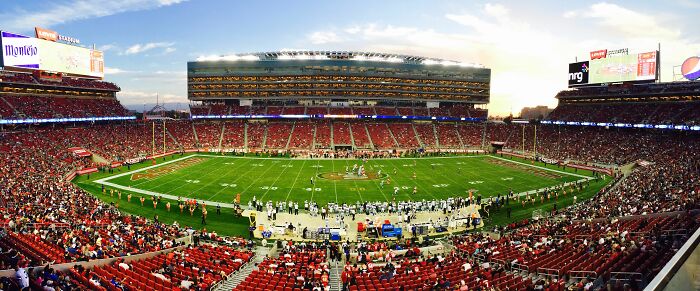 An expansive view of a football stadium packed with fans, reflecting funny encounters with American tourists.