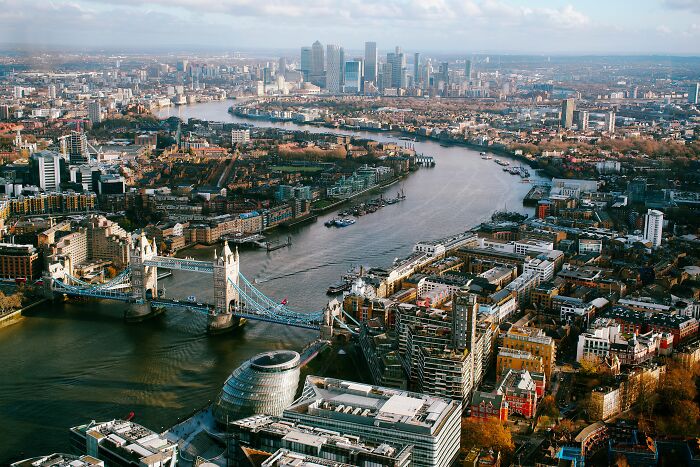An aerial view of the Thames River, Tower Bridge, and London skyline, popular sights for American tourists.