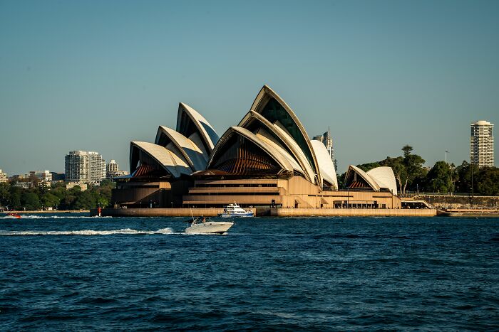 The Sydney Opera House on a sunny day with boats in the foreground, highlighting funny encounters with American tourists.