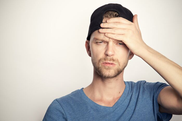 A man in a black cap looking exasperated, recalling embarrassing encounters with American tourists.